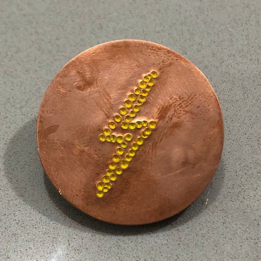 Copper marker with a yellow dot-punched lightning bolt