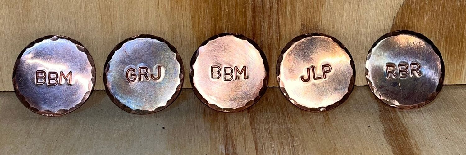 A matching set of copper ball markers stamped with initials